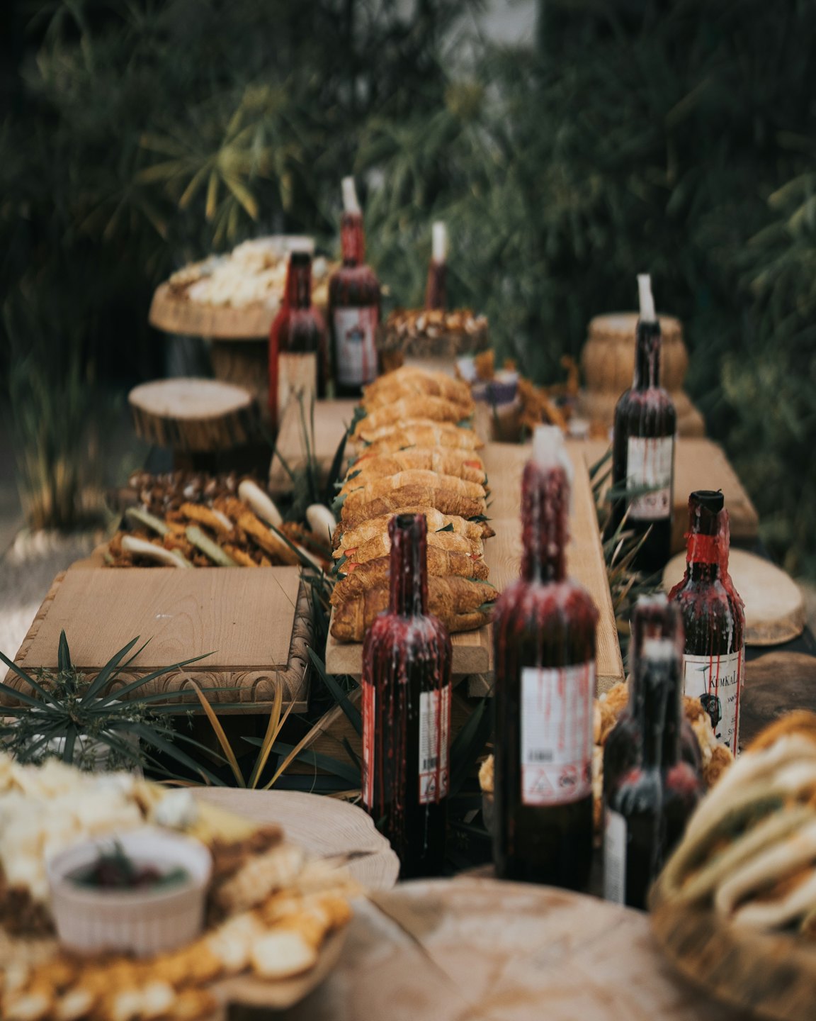 Handgemachte Sandwiches und Snacks auf Holzbrettern bei einem Buffet im Freien.