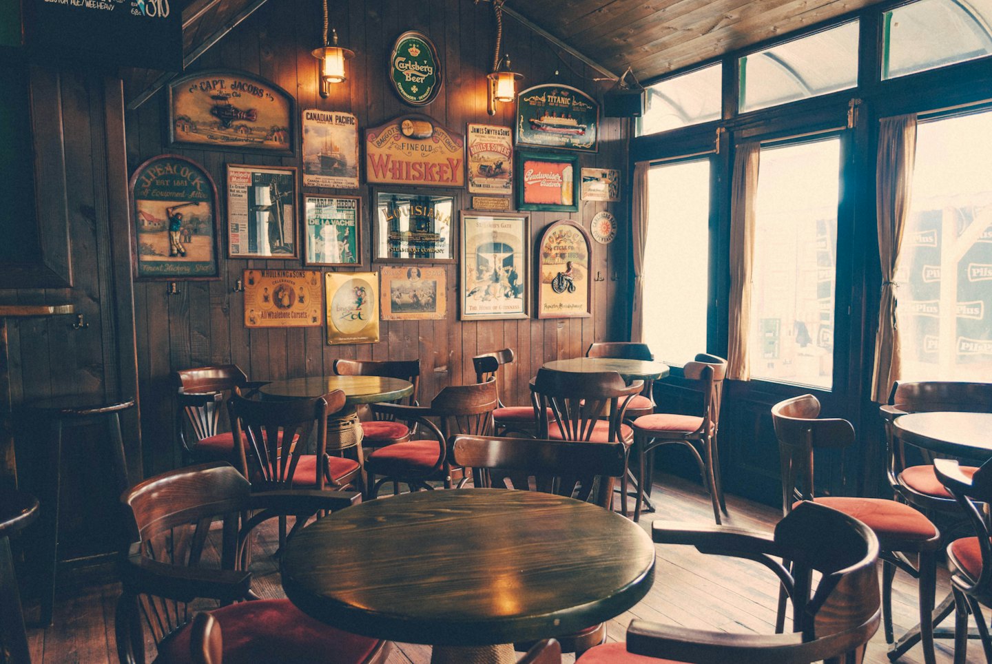 Leerer Pub-Innenraum mit Holztischen und Vintage-Schildern.